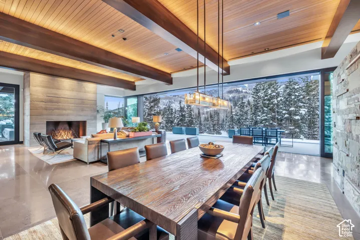 Spacious dining area featuring a long wooden table, a contemporary chandelier, and expansive windows