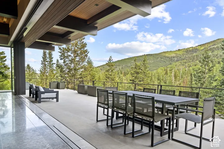 Expansive outdoor patio featuring a wood-panel ceiling, concrete flooring, and a contemporary metal railing