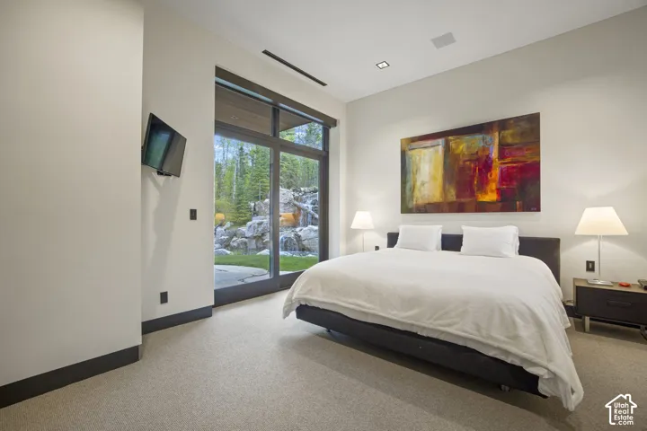 Room featuring floor-to-ceiling glass doors, recessed ceiling lighting, wall-mounted display, and light-toned carpeting