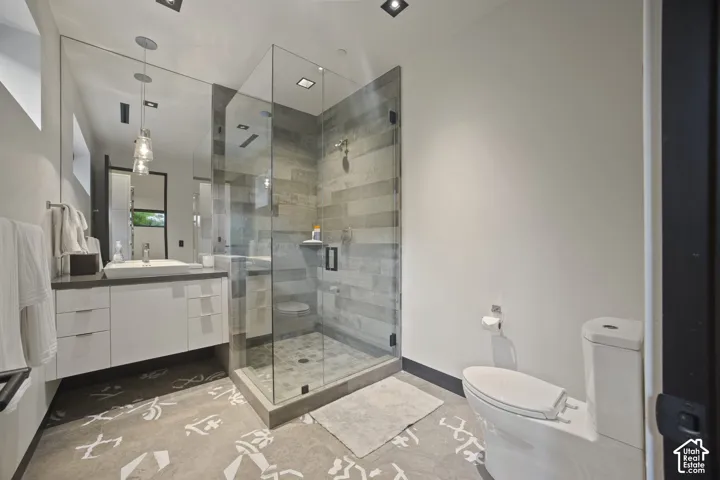 Modern bathroom featuring a glass-enclosed shower with horizontal tile, a floating vanity with a vessel sink, and patterned floor tile