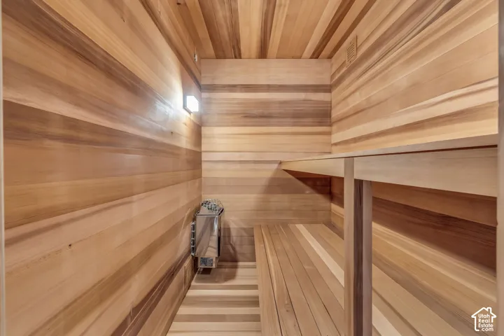 Wood-paneled sauna featuring a built-in heater, integrated bench seating, and overhead ventilation