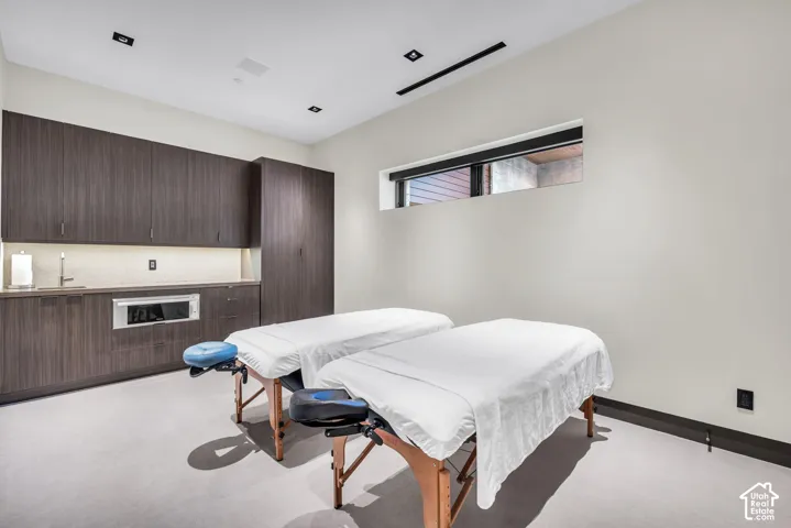 Spacious room featuring dark wood-finish cabinetry, a built-in stainless steel microwave, and a wet bar with an undermount sink