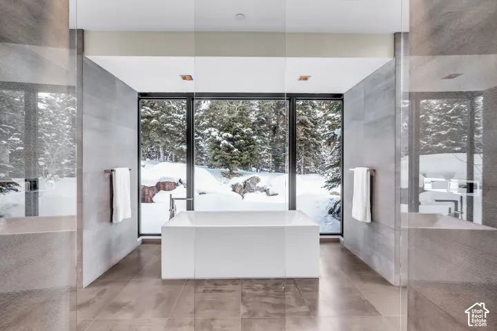 Freestanding soaking tub centered before expansive floor-to-ceiling windows