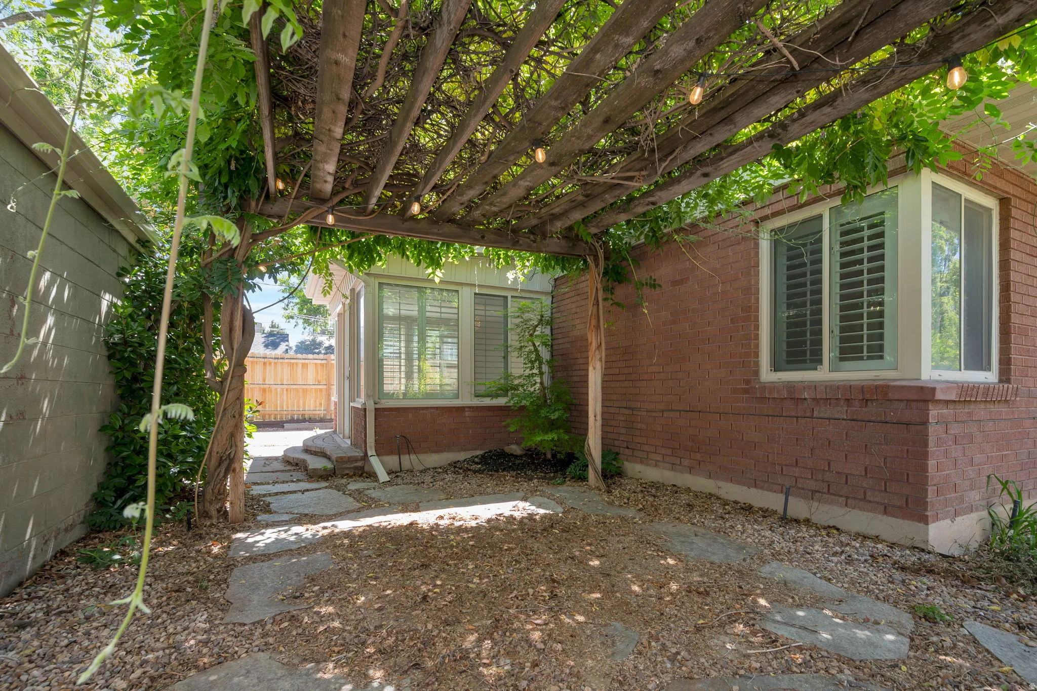 Lush vine-covered pergola over a stone-paver patio