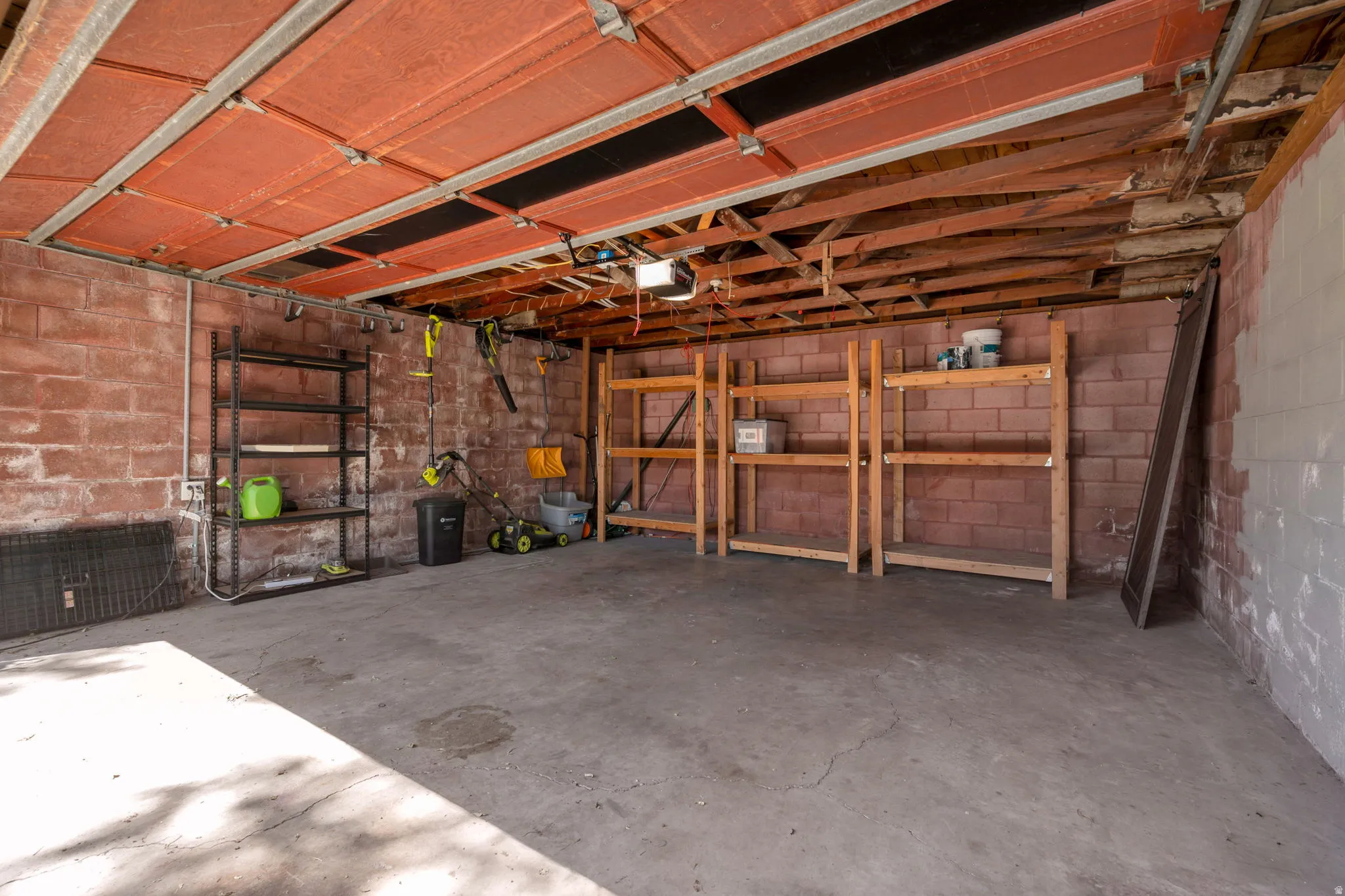 Garage space featuring exposed brick walls and concrete flooring
