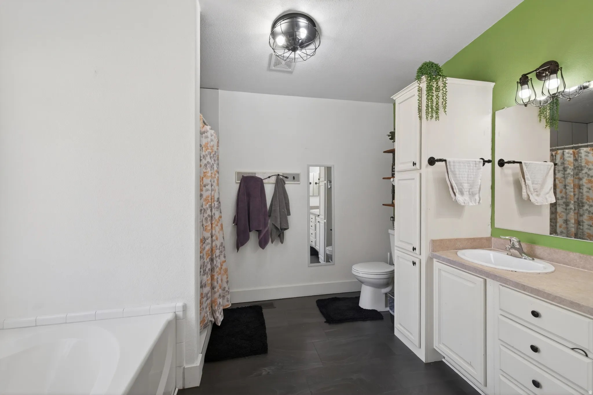 Bathroom featuring a single vanity with a white basin sink, light-colored countertop, and white cabinetry
