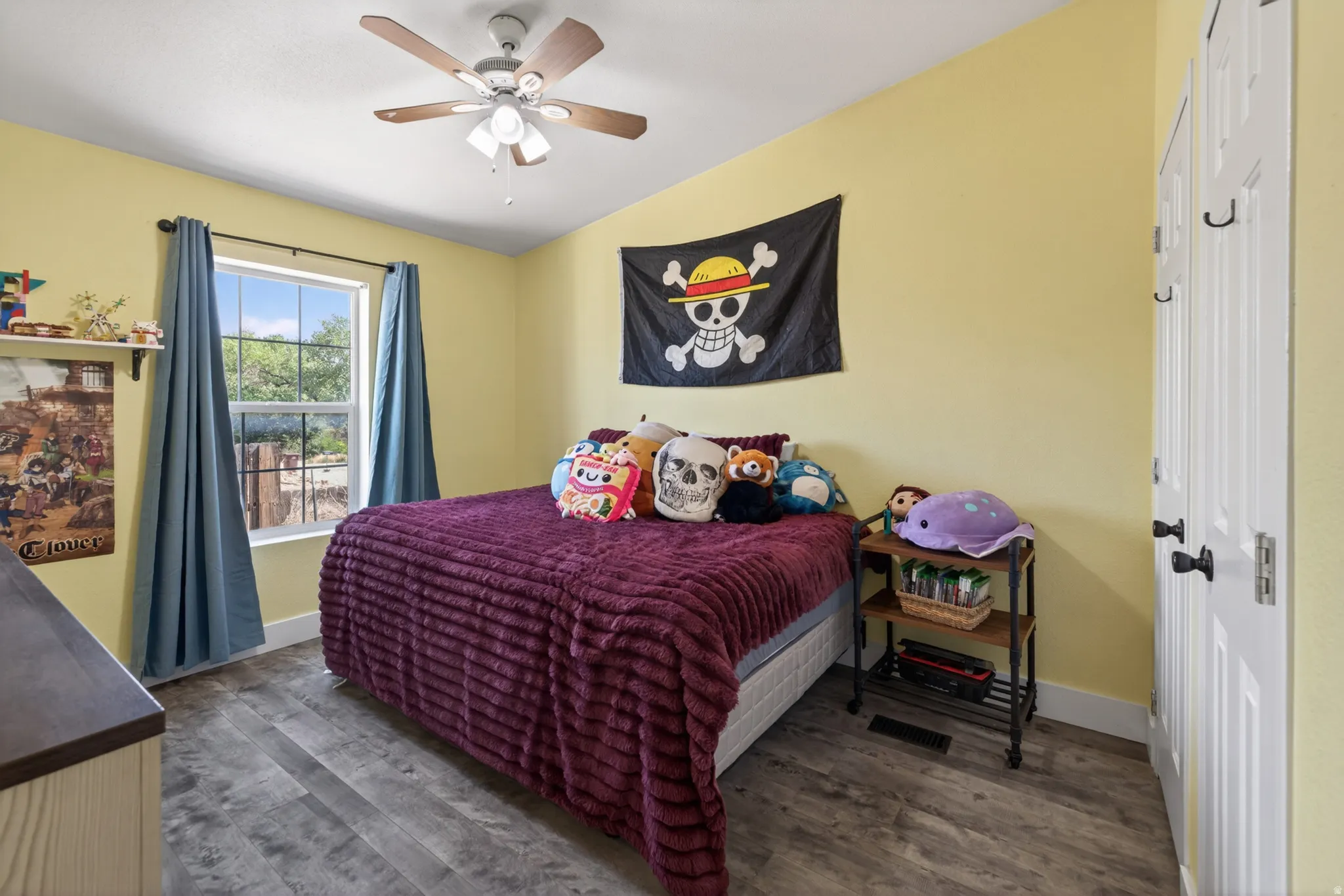 Bedroom featuring wood-finish flooring, a window with exterior views, and a ceiling fan with light fixture