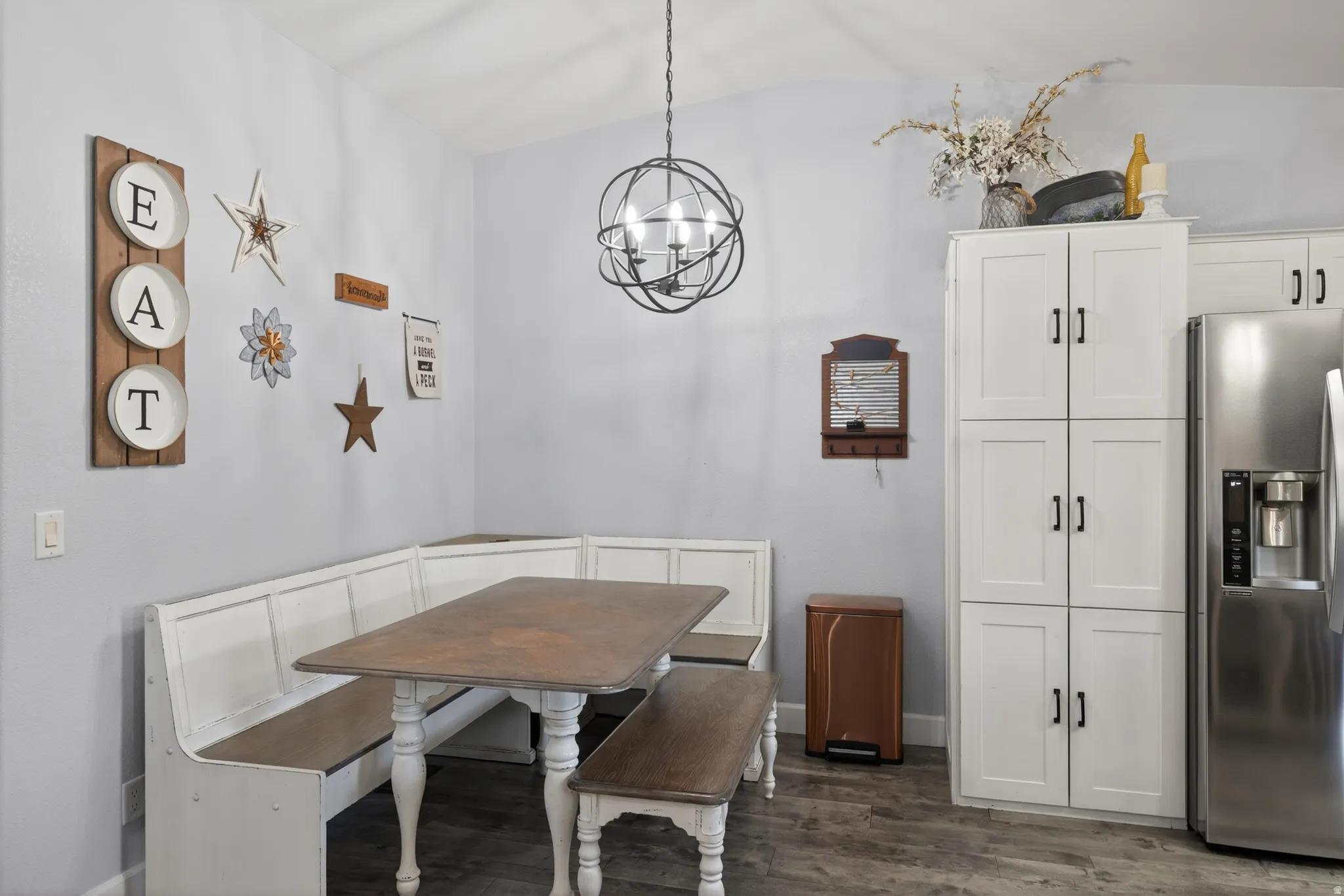 Dining area featuring a built-in bench seating, wood-finish flooring, and a contemporary spherical chandelier