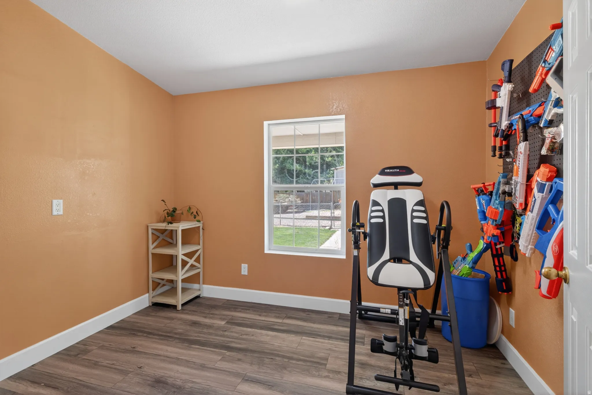 Room featuring wood-finish flooring, white baseboards, and a window with exterior views