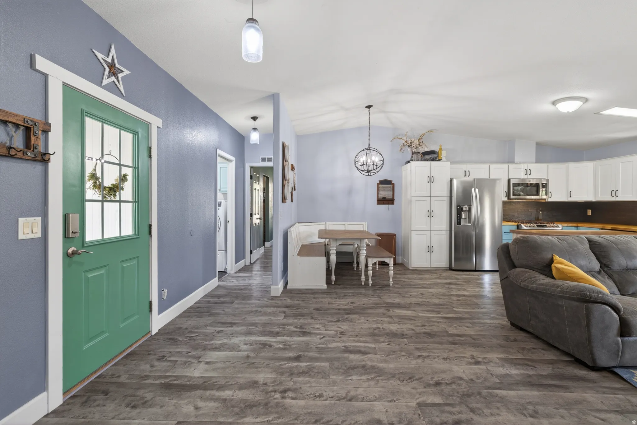 Open-concept living space with wood-finish flooring, vaulted ceilings, and a light blue wall finish