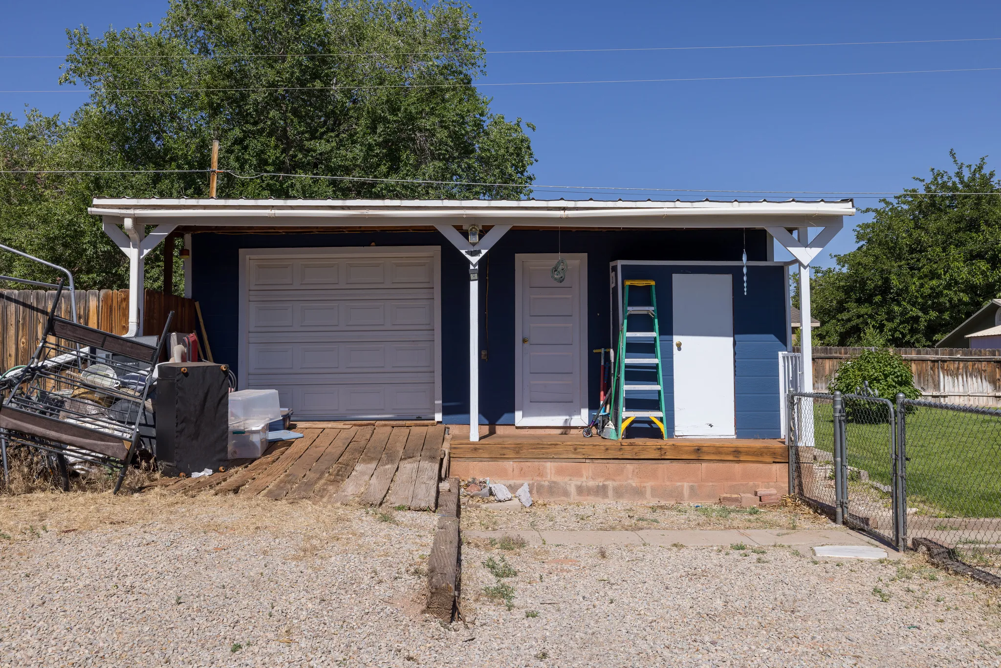Detached outbuilding with blue siding, white trim, and a covered porch