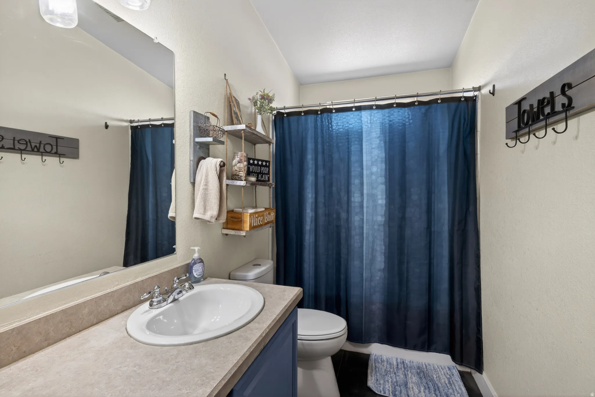 Bathroom featuring a single basin vanity with an oval sink, chrome faucet, and a light-toned countertop
