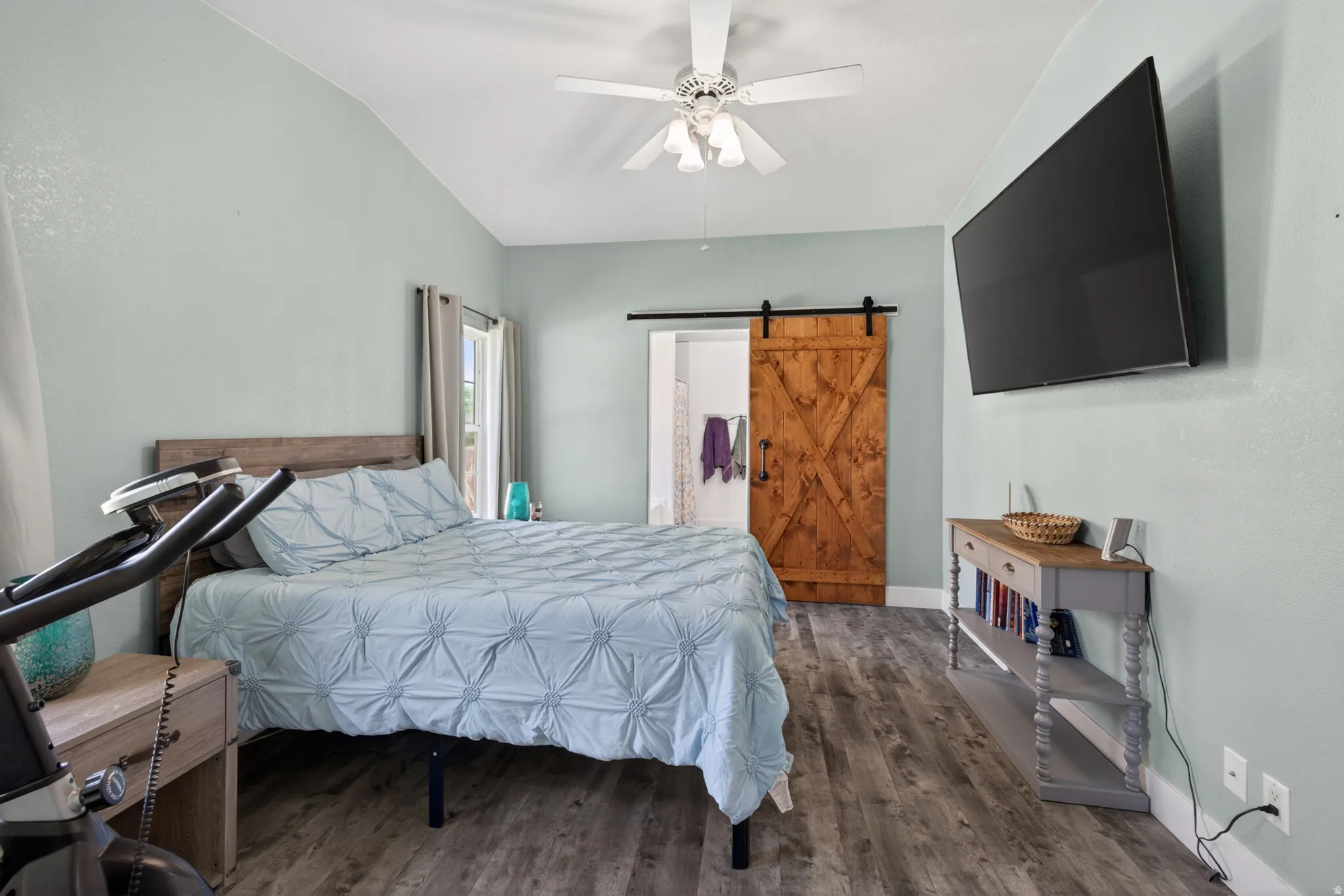 Vaulted ceiling bedroom featuring wood-finish flooring and a ceiling fan