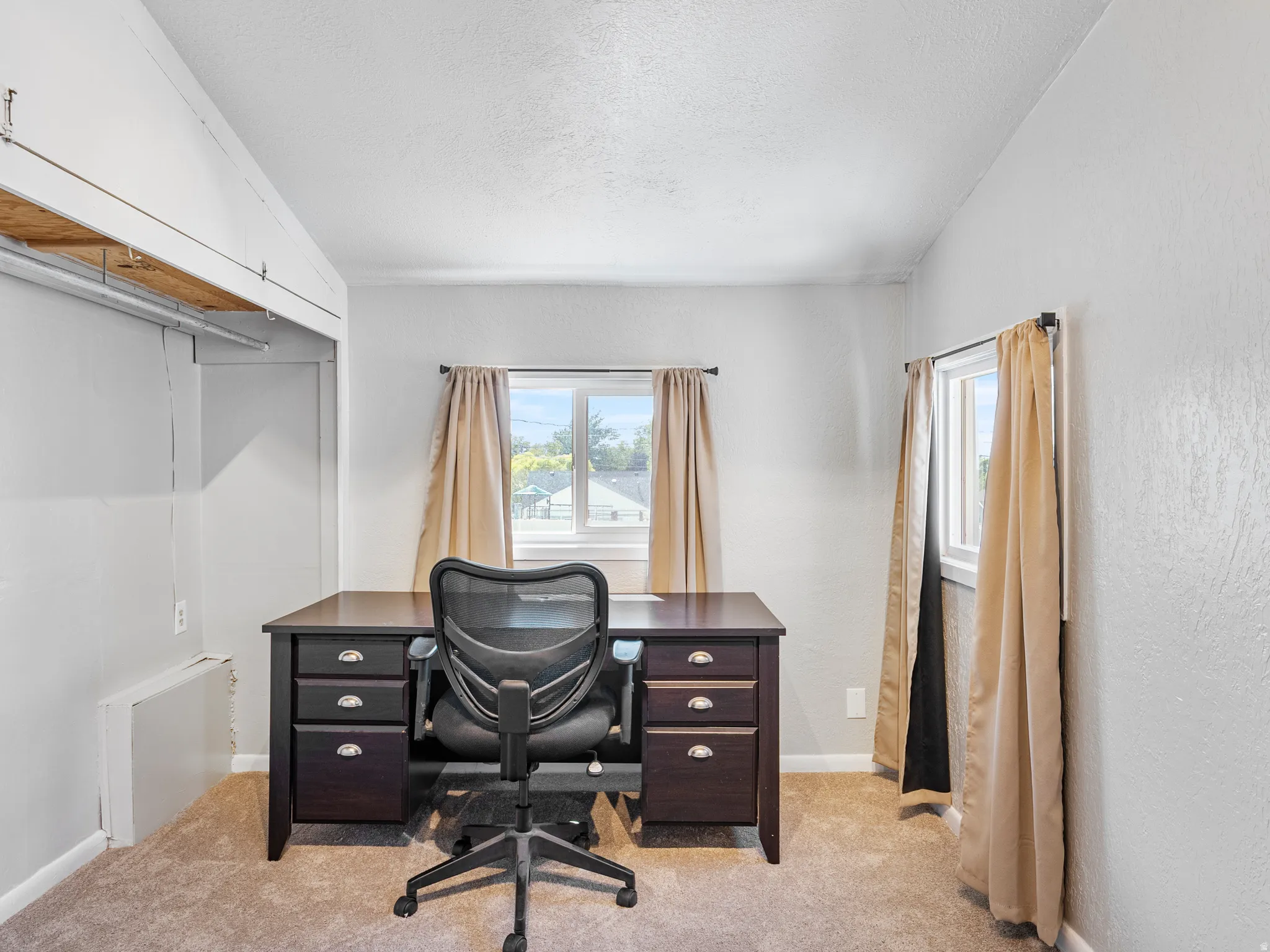 Carpeted room featuring multiple windows with natural light, neutral wall colors, and built-in shelving