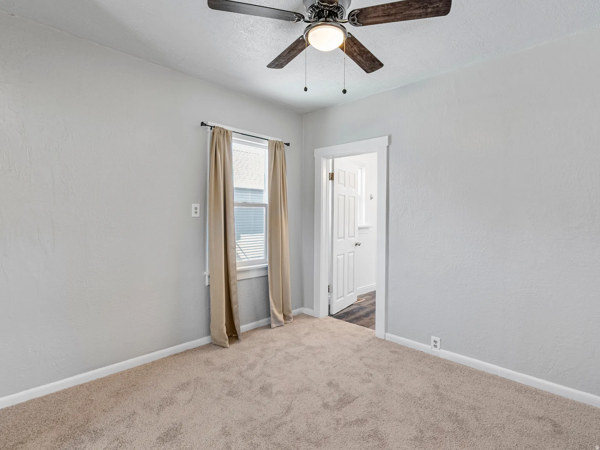 Bedroom featuring wall-to-wall carpeting, light-toned wall paint, a window with blinds, and a ceiling fan with integrated lighting