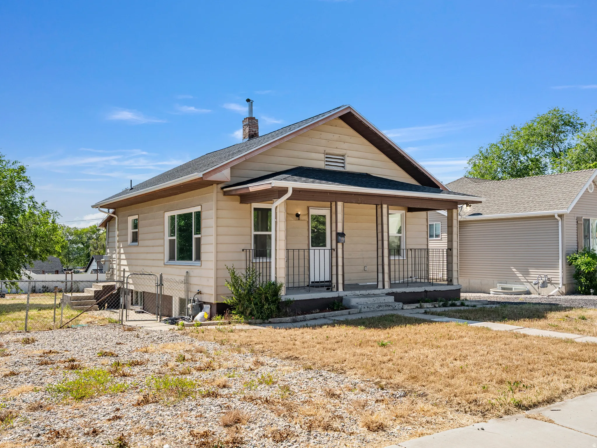 Traditional style residence featuring a covered front porch with iron railings, light beige siding, and a gabled roof