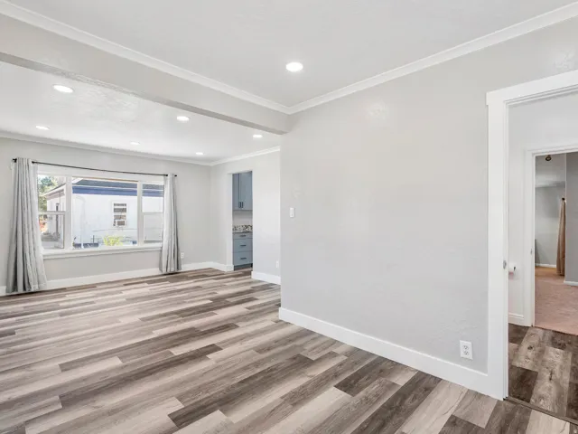 Spacious room featuring wood-finish flooring, recessed lighting, and a large window with window treatments