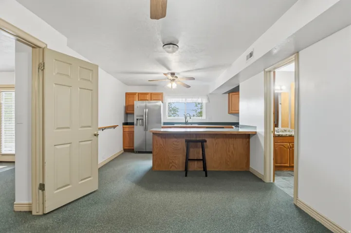 Kitchen area featuring wood-finish cabinetry, stainless steel refrigerator, and breakfast bar with countertop