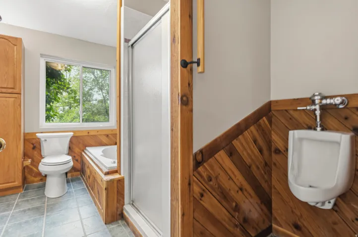 Bathroom featuring wood-paneled wainscoting, tiled flooring, a built-in tub, and a separate shower enclosure with a sliding door