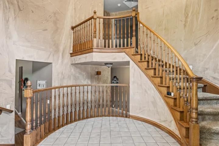 Grand two-story entryway featuring a curved staircase with wood balusters and handrails