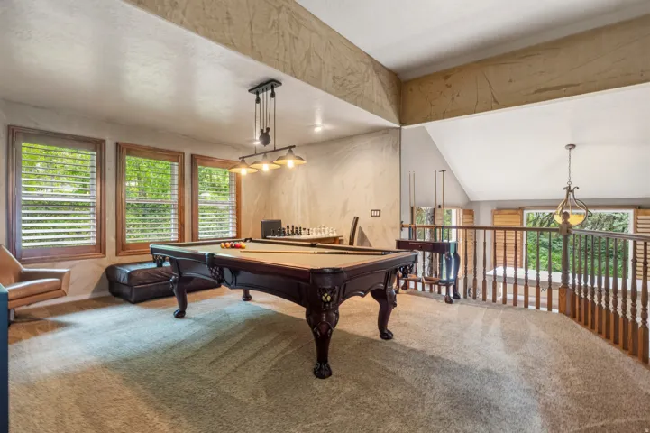Carpeted upper-level bonus room with a vaulted ceiling and textured wall finishes