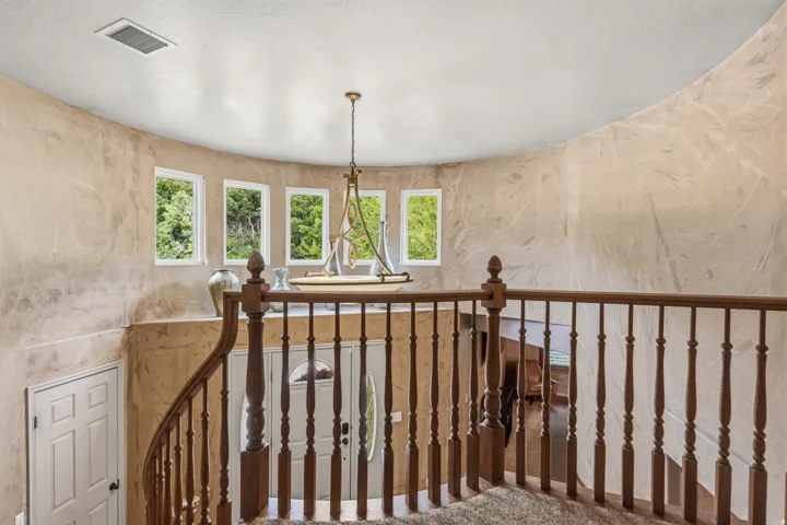 Curved stairwell with wood balusters and a decorative chandelier
