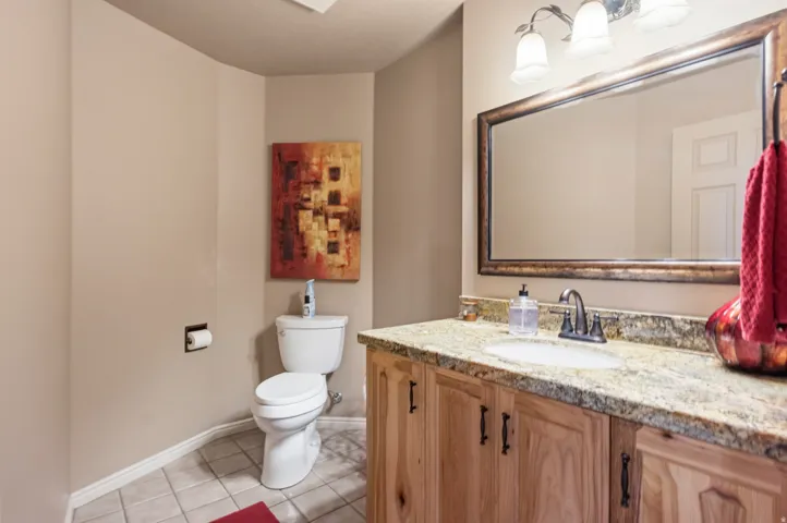 Vanity with a granite countertop, undermount sink, and wood-finish cabinetry featuring dark hardware