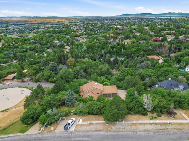 Brick exterior residence with a multi-car garage, mature landscaping, and white fencing bordering the property