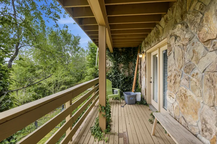 Expansive wood-finish deck with a wood railing and natural stone exterior