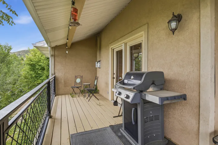 Covered deck featuring a wood-finish floor and black metal railing