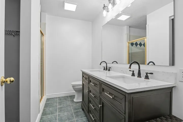 Double vanity with dark wood-finish cabinetry, white countertops, and dual undermount sinks with matte black fixtures