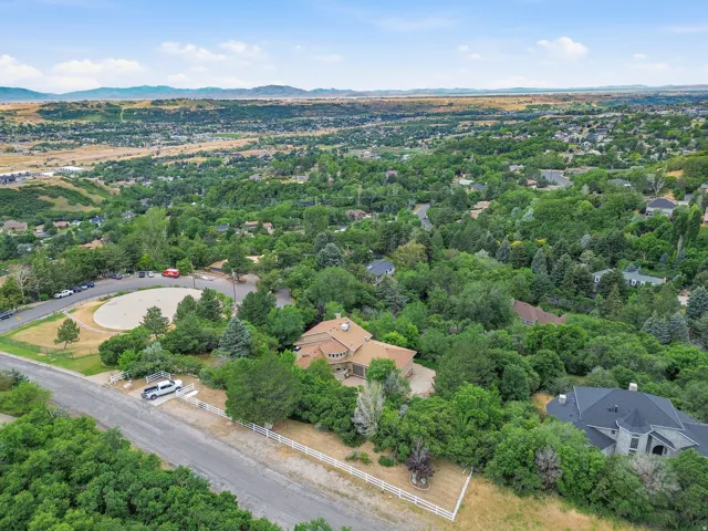 Expansive hillside property featuring a multi-level residence with a distinct curved facade, surrounded by mature trees