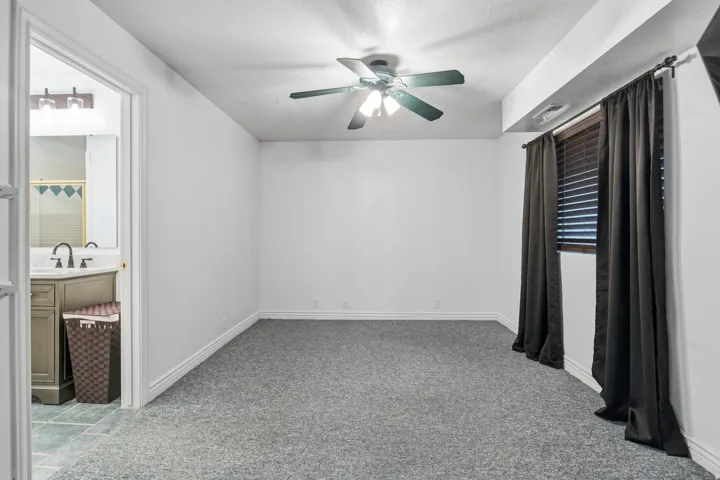 Spacious room with gray textured carpeting, white walls, and a ceiling fan with integrated lighting