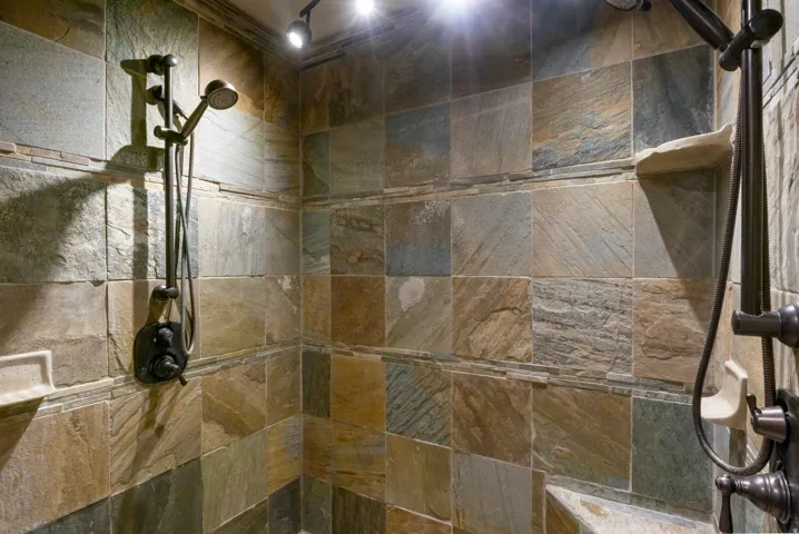 Shower enclosure featuring multi-toned slate tile walls and a built-in bench