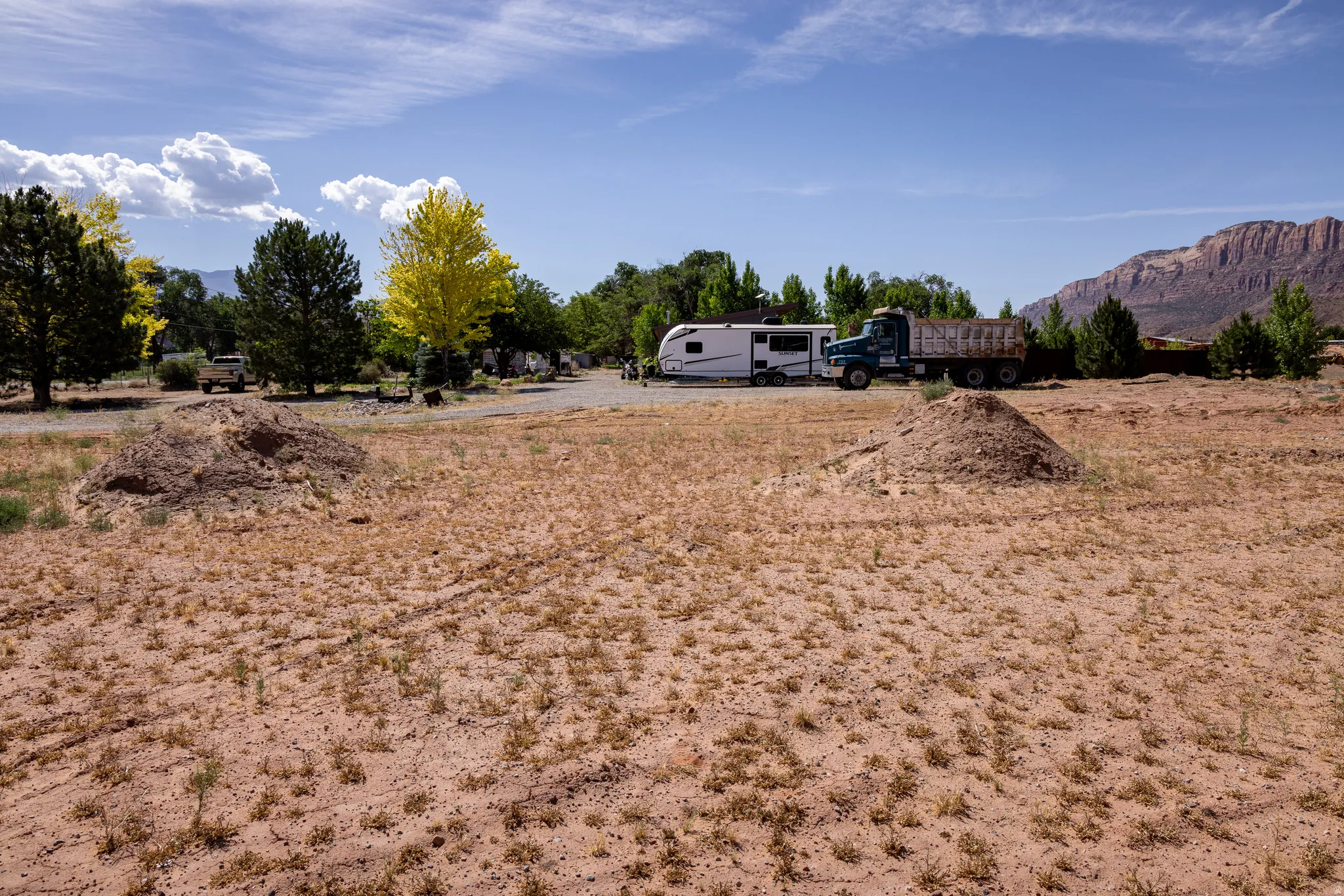 Expansive undeveloped lot featuring a natural desert landscape with scattered vegetation, surrounded by mature trees