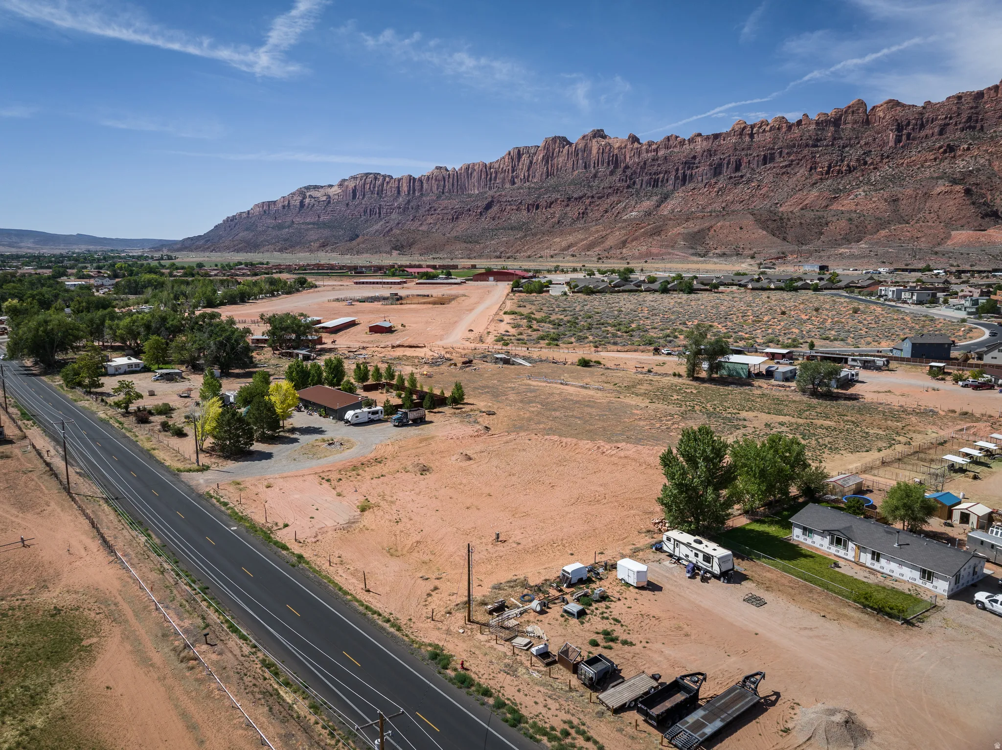 Expansive rural landscape featuring a paved roadway, scattered structures, and natural desert vegetation