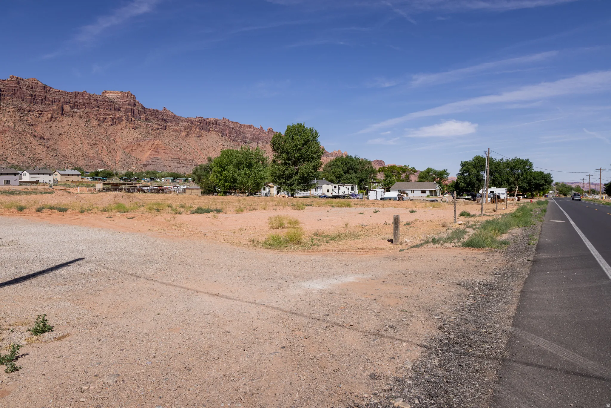 Expansive undeveloped lot featuring a natural desert landscape, mature trees, and direct road frontage