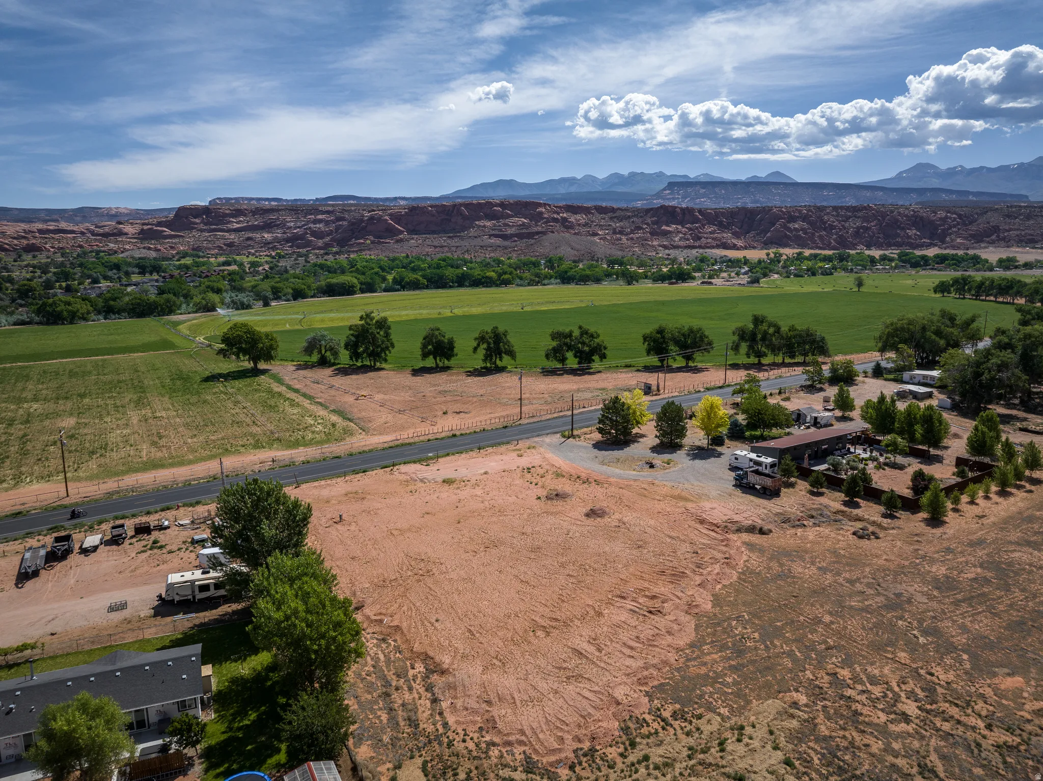 Expansive acreage featuring a paved road, scattered mature trees, and a distant mountain range