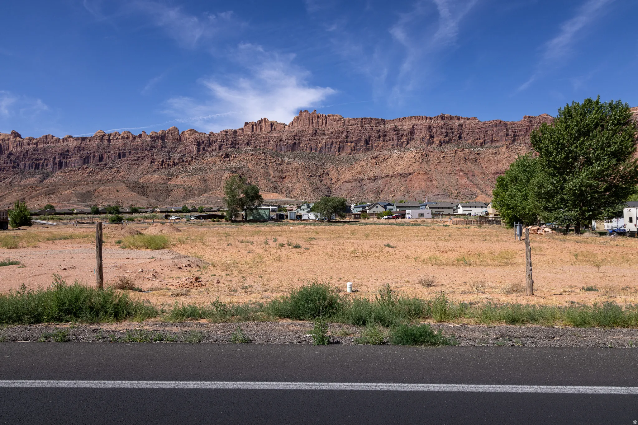 Expansive undeveloped land featuring natural vegetation and distant residential structures