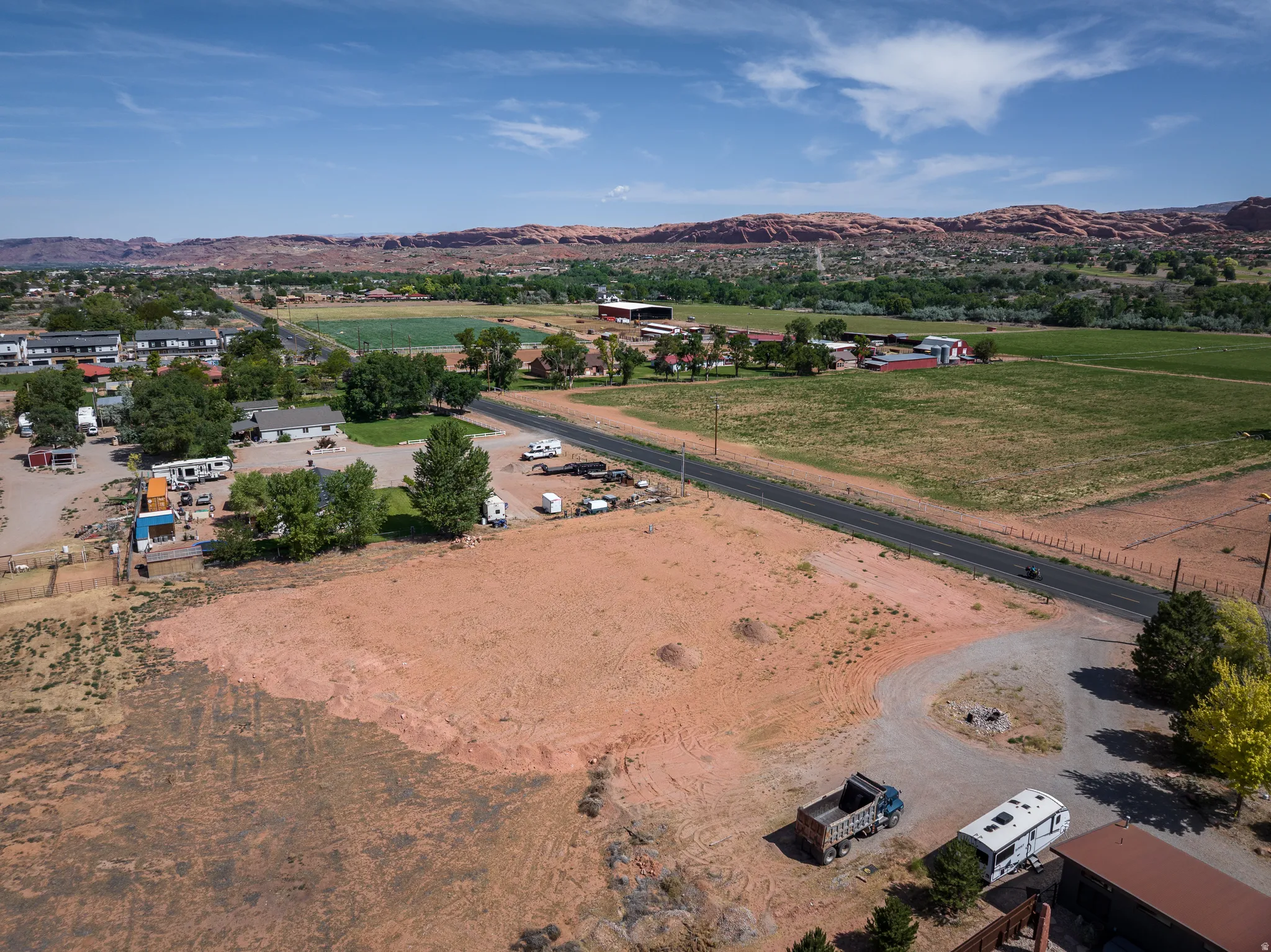 Expansive cleared lot featuring a natural earth tone base, partial gravel driveway, and mature trees on the property's perimeter
