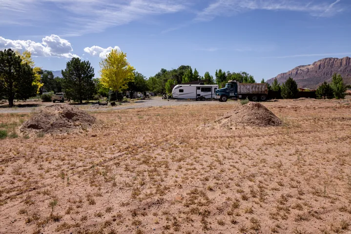 Expansive undeveloped lot featuring a natural desert landscape with scattered vegetation, surrounded by mature trees