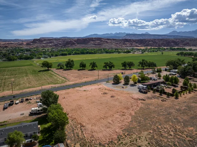 Expansive acreage featuring a paved road, scattered mature trees, and a distant mountain range