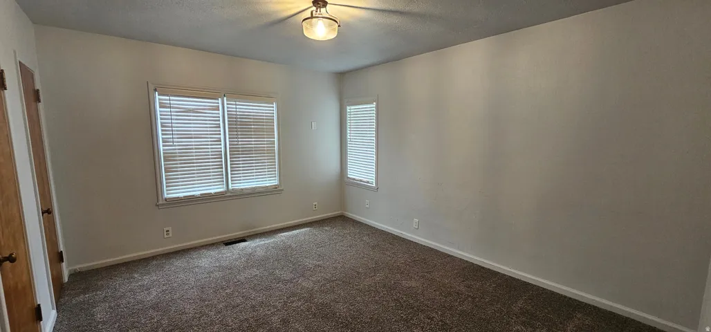 Bedroom featuring neutral wall tones and dark carpet flooring