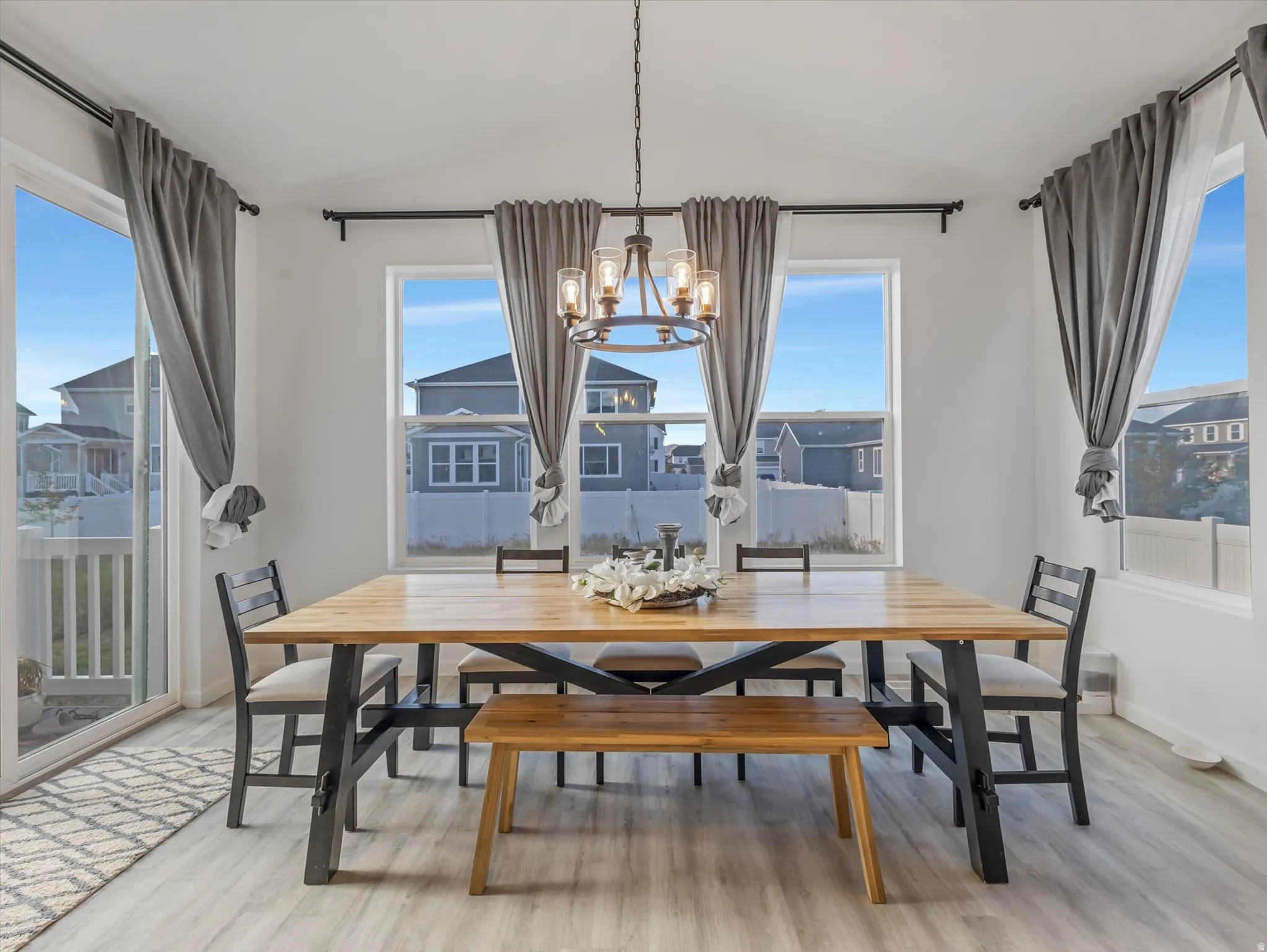 Dining area featuring a contemporary chandelier, abundant natural light from multiple windows, and a sliding glass door to an exterior space