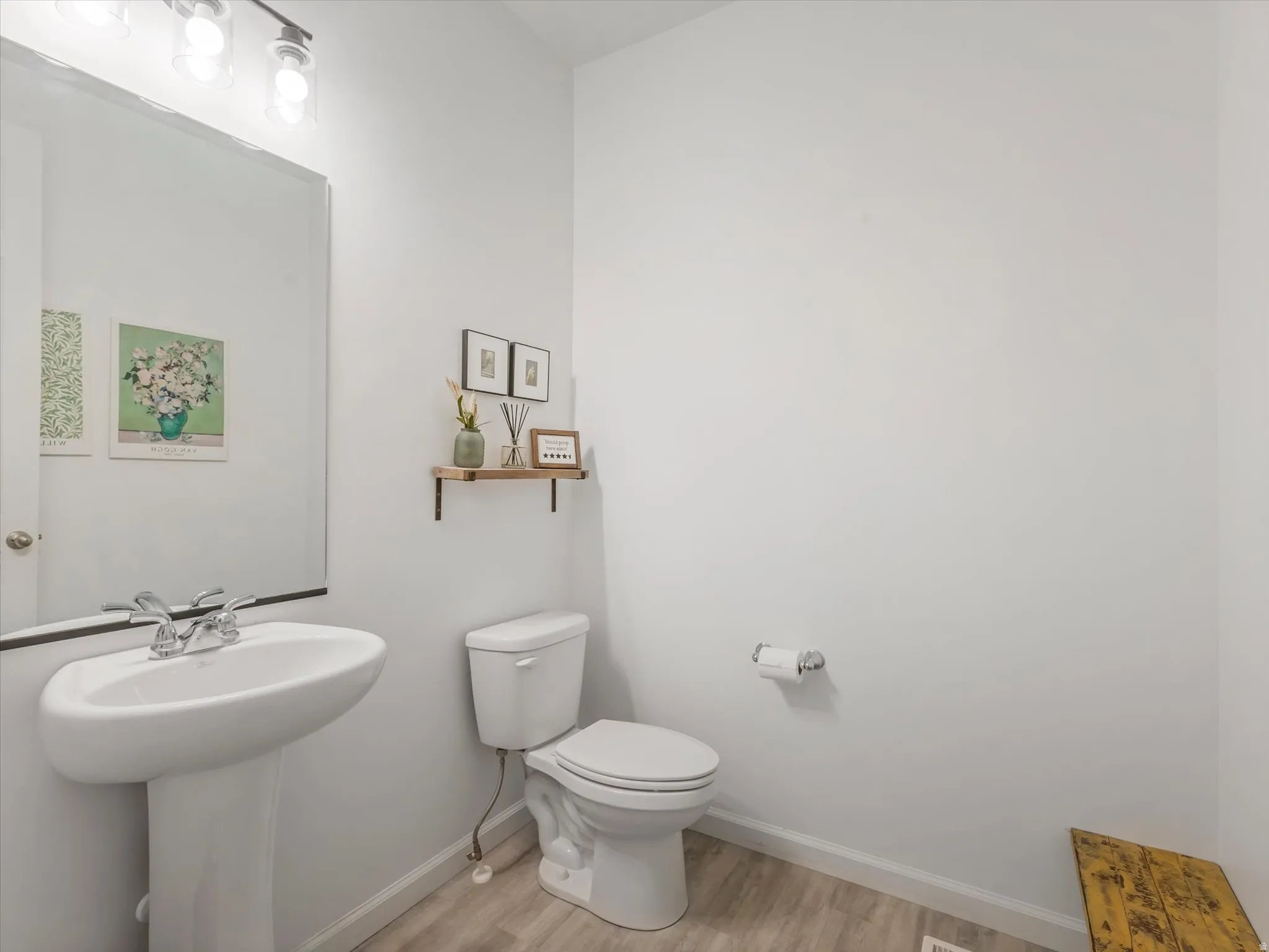 Pedestal sink with chrome faucet, large vanity mirror, and modern three-bulb vanity lighting