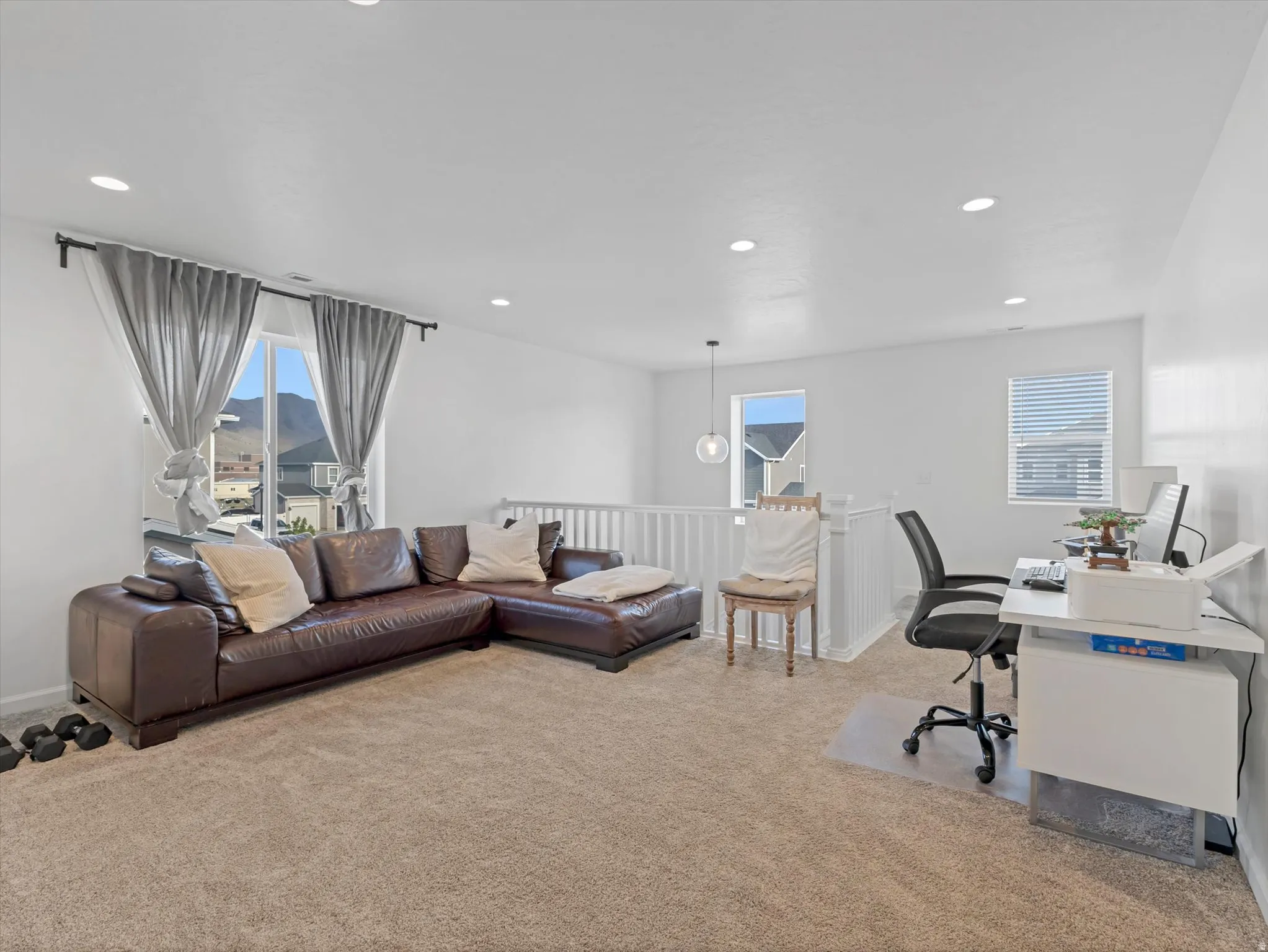 Carpeted open loft space featuring recessed lighting, a white painted railing, and multiple windows