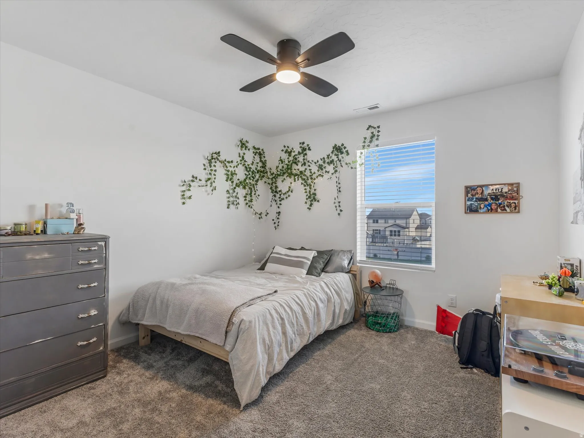 Carpeted interior room featuring a ceiling fan with integrated lighting, a single window with blinds, and white walls