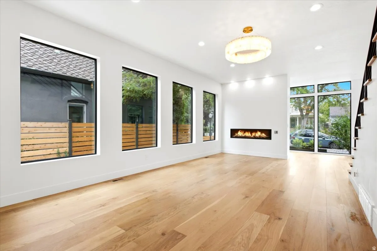 Spacious room with light wood-finish flooring, a linear fireplace, and recessed lighting