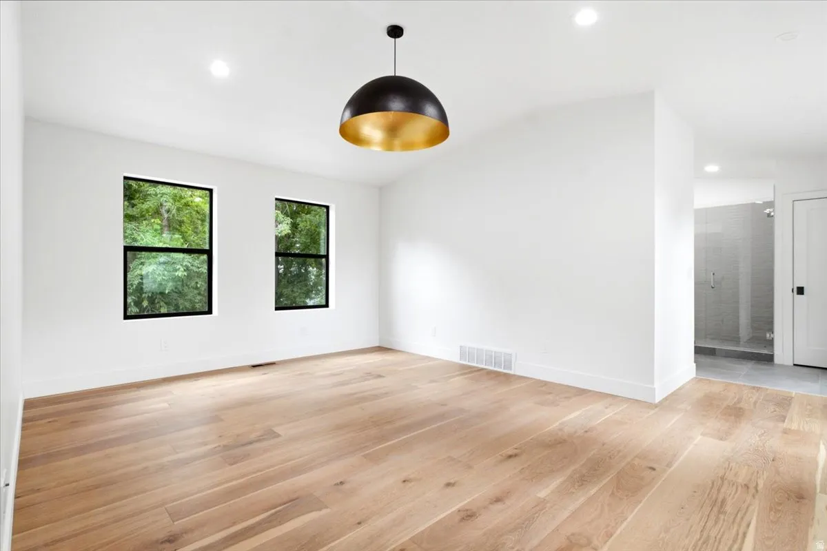 Primary Bedroom featuring wood-finish flooring, recessed lighting, and a contemporary black and gold pendant light fixture