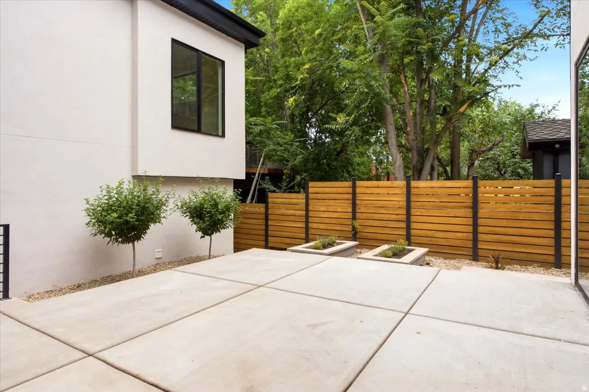 Spacious concrete patio featuring horizontal wood fencing with black posts